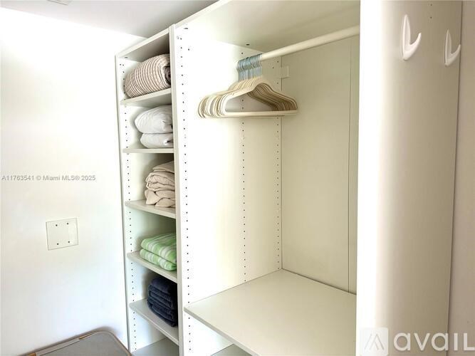 A white closet with clothes on shelves and hangers.