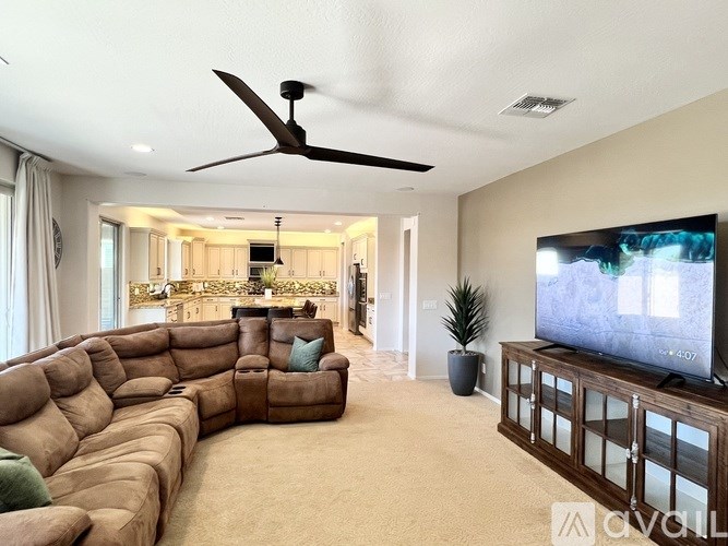 A brown dresser with a round mirror above it and a chair with a grey pillow beside it.