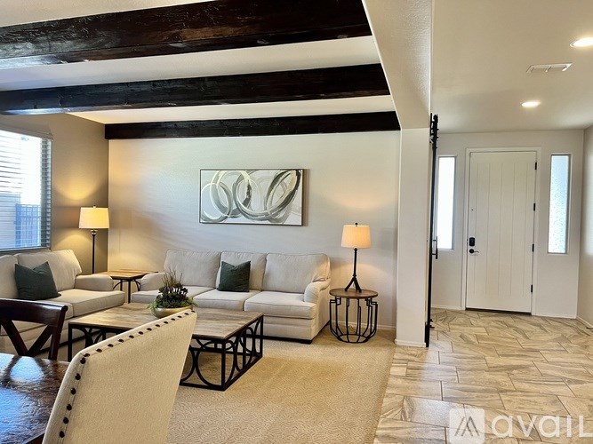 A living room with a white couch, a coffee table, and a painting on the wall.