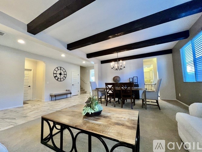 A living room with a white couch, a wooden coffee table, and a dining table with chairs.