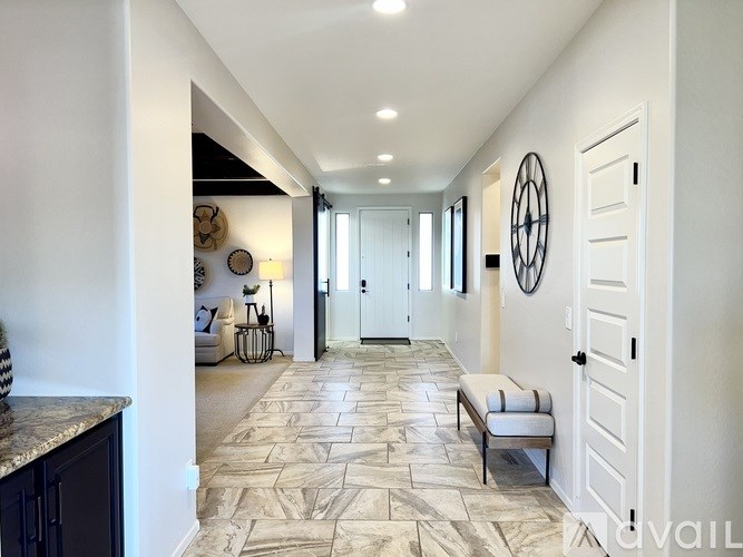 A hallway with a bench and a circular mirror on the wall.