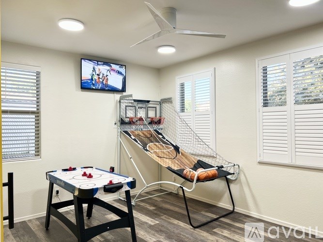 A room with a pool table and a television playing a sports game.