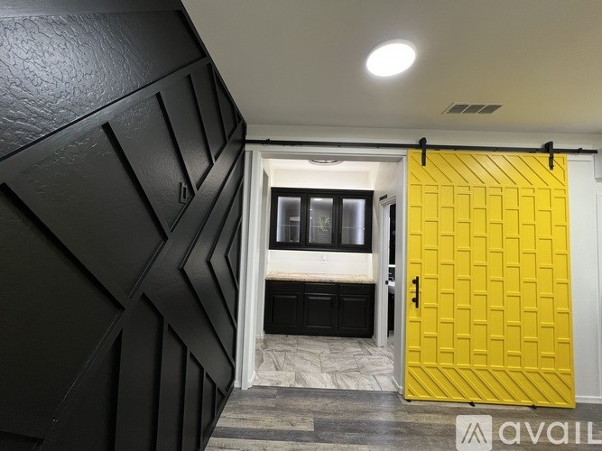 A yellow door with a black wall behind it.