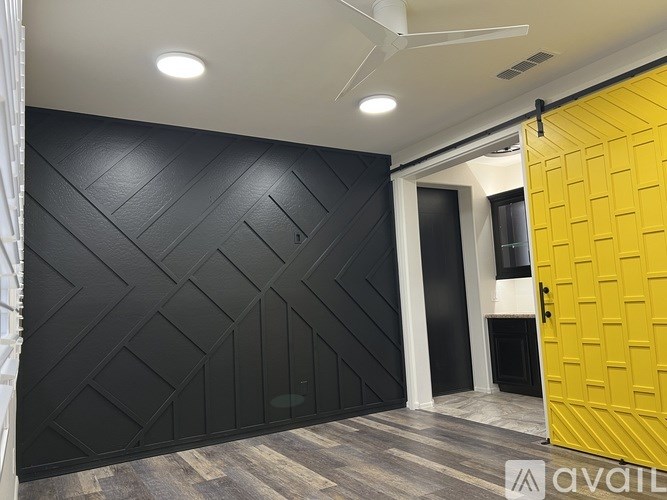 A room with a black wall and a yellow door.