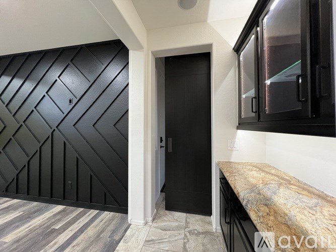 A black door with a handle is in a white room.