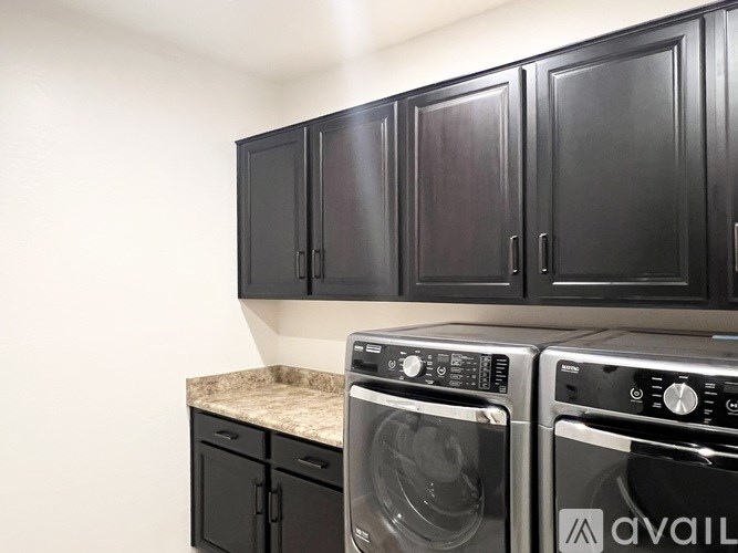 A black washing machine and dryer in front of a wall.