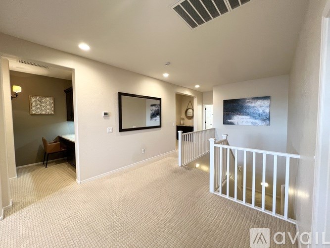A living room with a white railing and a painting on the wall.