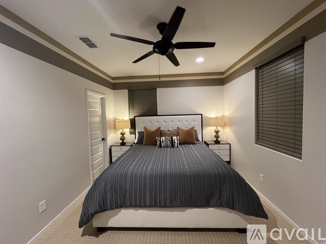 A bedroom with a bed, pillows, and a ceiling fan.