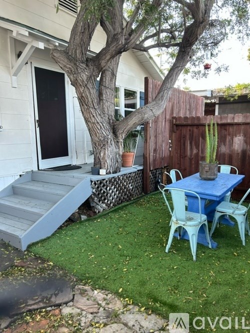 A patio with a table and chairs under a tree.