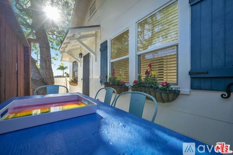 A pool table is in the foreground of a sunny backyard.