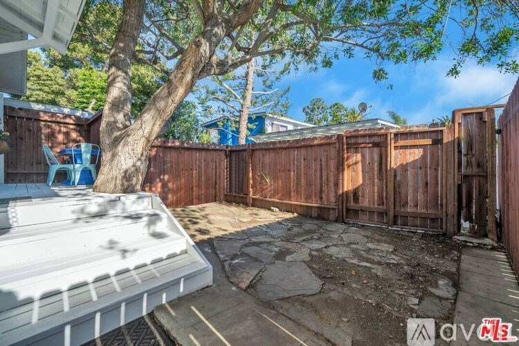 A backyard with a white fence and a tree.