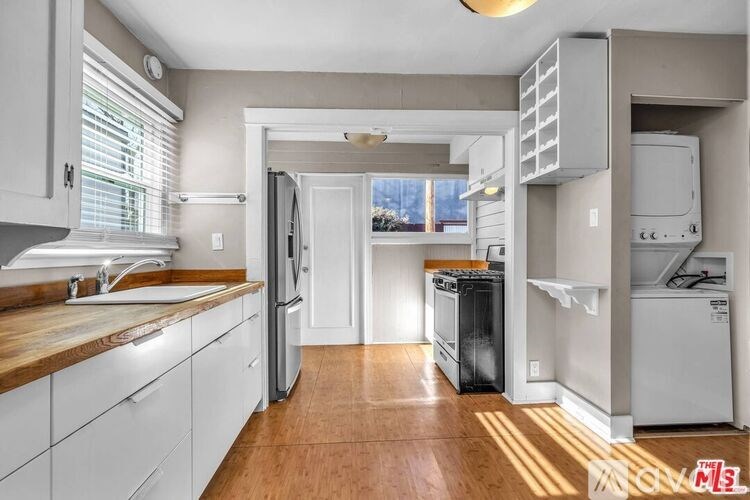 A kitchen with white cabinets and a wooden countertop.
