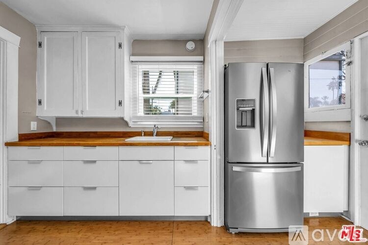 A kitchen with white cabinets and a stainless steel refrigerator.