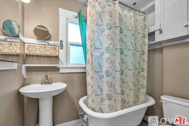 A bathroom with a shower curtain that has a pattern of green leaves and brown baskets on it.
