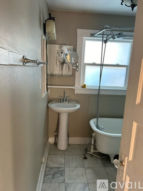 A bathroom with a white sink and a bathtub with a shower head.