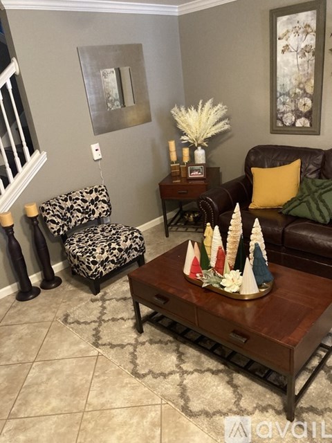 A living room with a leather couch, a coffee table with a vase of flowers, and a mirror on the wall.