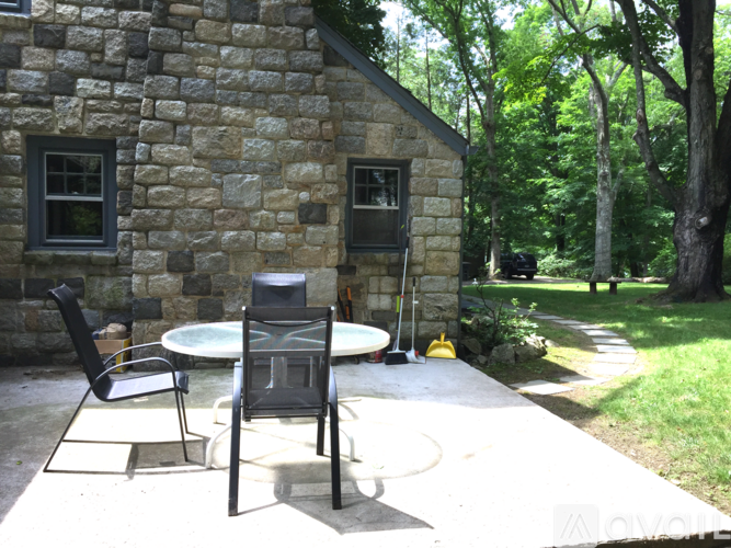 A patio with a table and chairs is in front of a stone building.