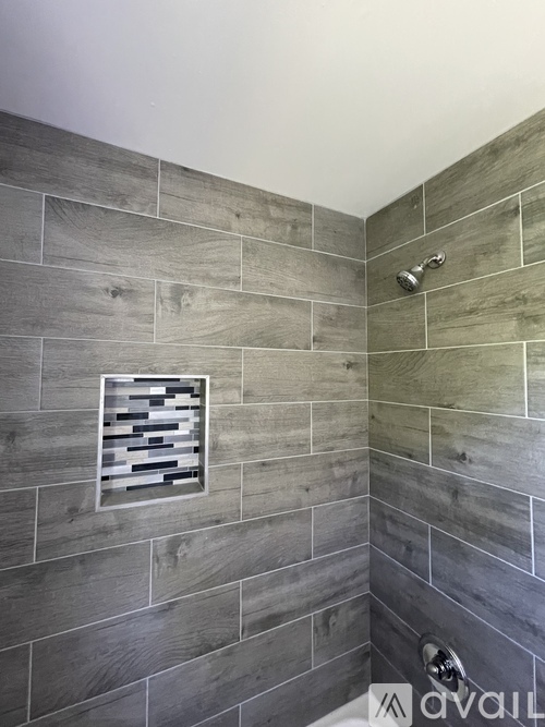 A bathroom with a grey tiled wall and a vent.