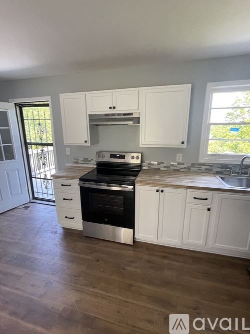 A kitchen with a stove top oven and white cabinets.