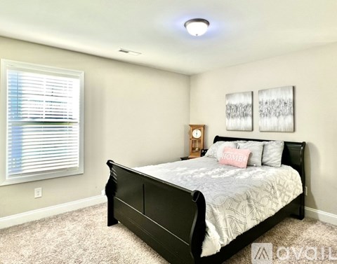 A bedroom with a large bed and a window with blinds.