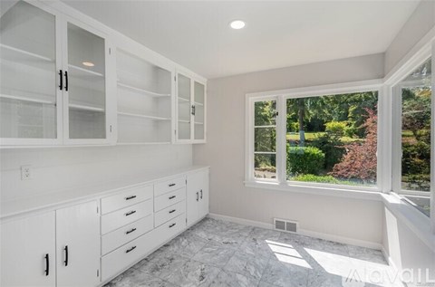 A spacious kitchen with white cabinets and marble flooring.