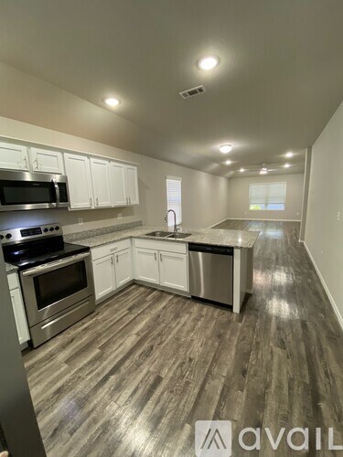 A kitchen with white cabinets and a wooden floor.