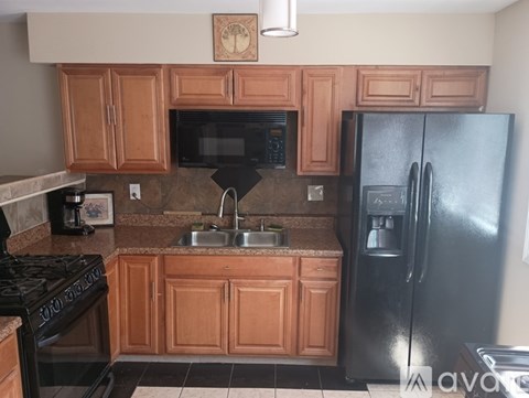 A kitchen with wooden cabinets and a black refrigerator.