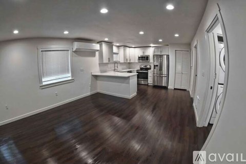 A kitchen with dark wood floors and white walls.