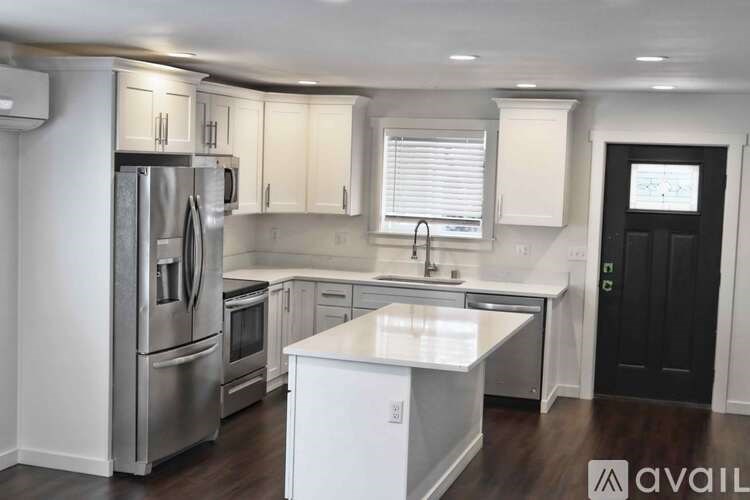 A kitchen with white cabinets and a stainless steel refrigerator.