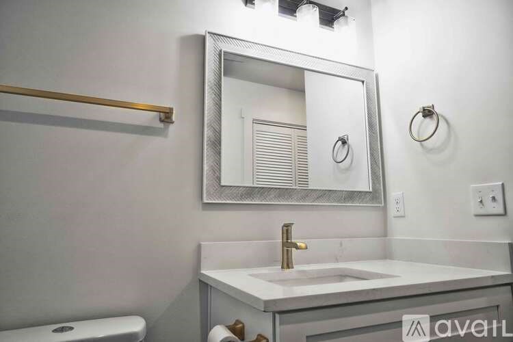 A bathroom with a sink, mirror, and toilet paper holder.