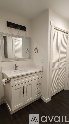 A stainless steel refrigerator stands in a kitchen with white cabinets.
