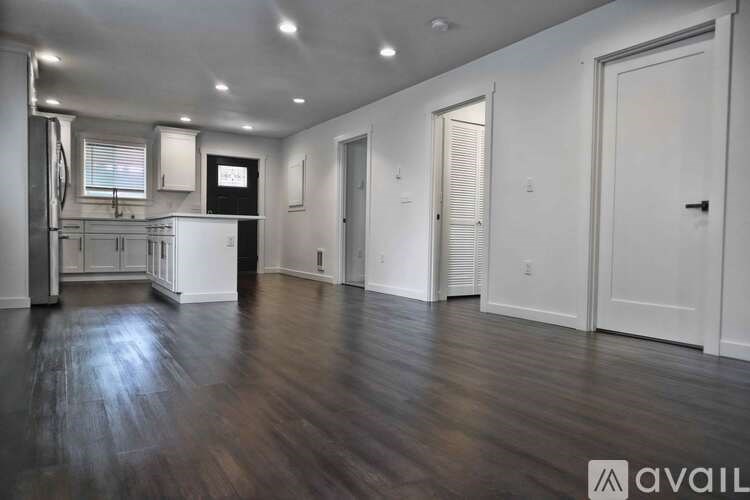 A spacious room with wooden floors and white walls.