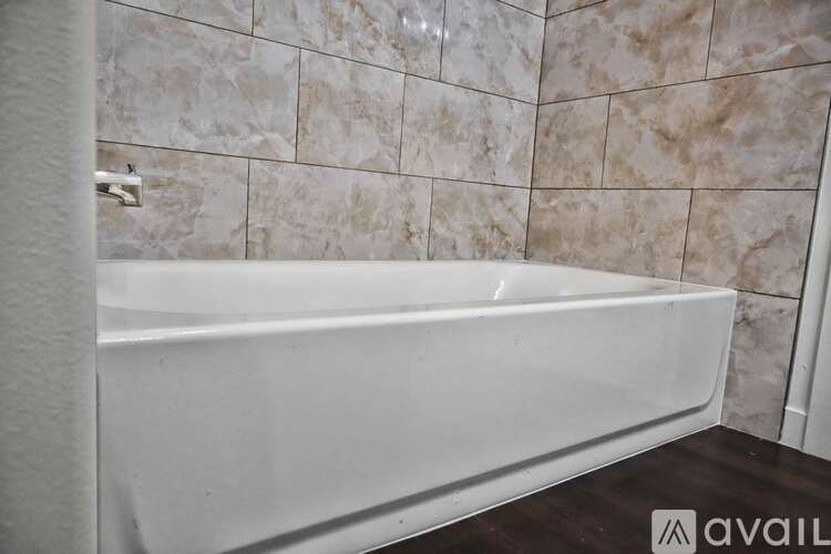 A white bathtub is installed in a bathroom with marble tiles.