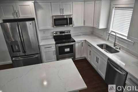 A kitchen with white cabinets and a marble countertop.