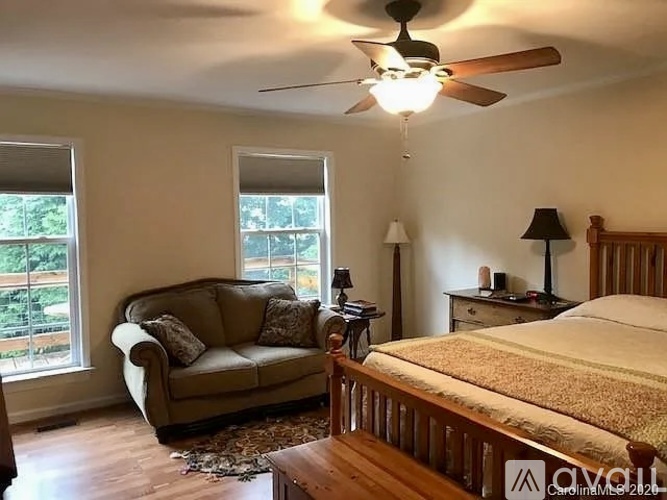 A bedroom with a bed, a couch, and a ceiling fan.