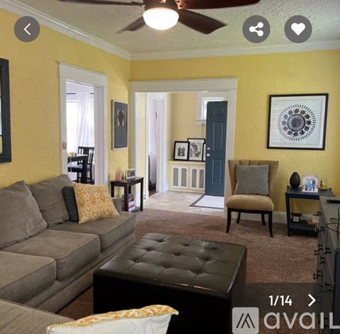 A living room with a grey couch and a black ottoman.