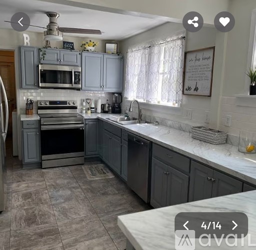 A kitchen with a marble countertop and grey cabinets.