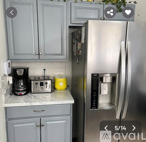 A kitchen with a refrigerator, toaster, and coffee maker.