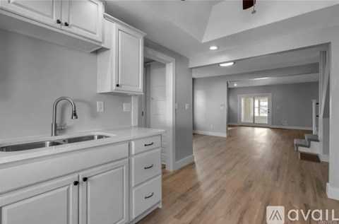 A modern kitchen with white cabinets and a wooden floor.