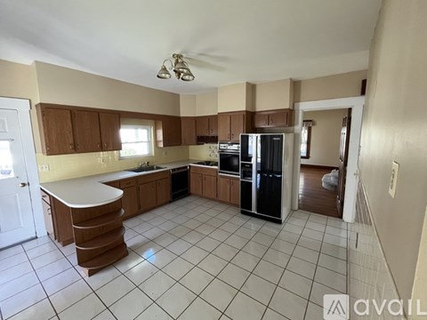 A kitchen with white tiled floors and wooden cabinets.