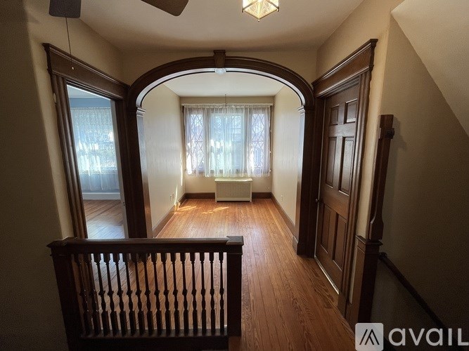 A room with wooden floors and a window with curtains.