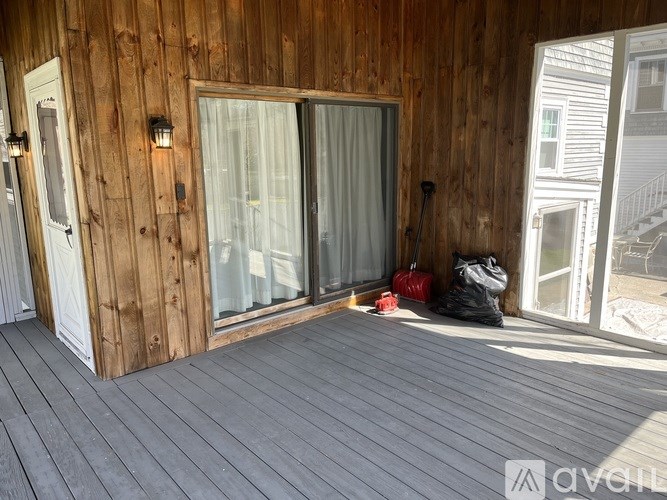 A balcony with a wooden wall and a sliding glass door.