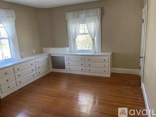 A room with wooden floors and white furniture.