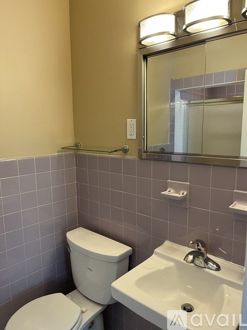 A bathroom with a toilet, sink and mirror.