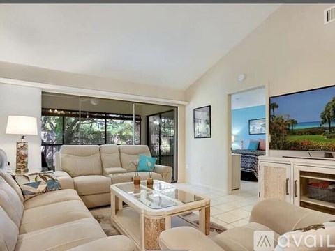 A living room with a large sectional sofa and a flat screen TV mounted on the wall.