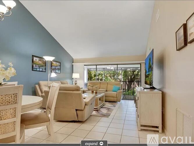A living room with a television, couches, and a dining table.