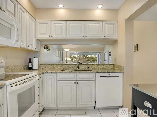 A kitchen with white appliances and cabinets.