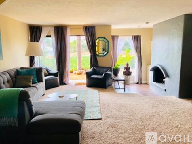 A living room with a grey couch, a black armchair, and a rug.