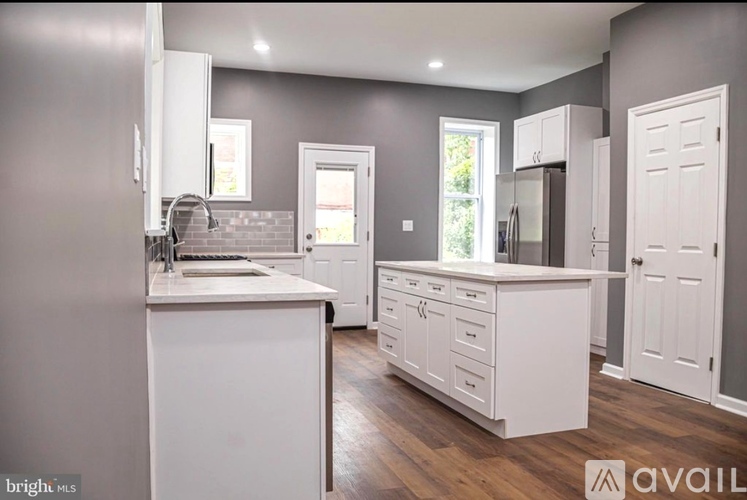A kitchen with white cabinets and a wooden floor.