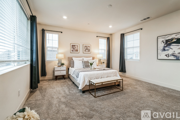 A bedroom with a large bed, two nightstands, and a window with curtains.